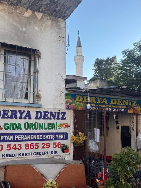 Kleiner Laden an einer Straßenecke, dahinter ein Minarett