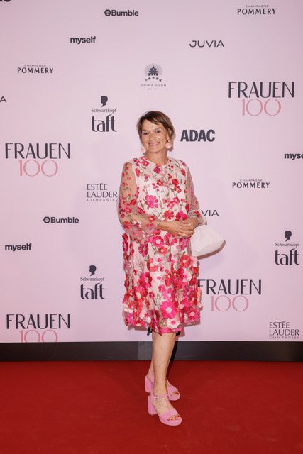 Claudia Wuttke vor der Fotowand der Veranstaltung 5 Jahre Frauen100